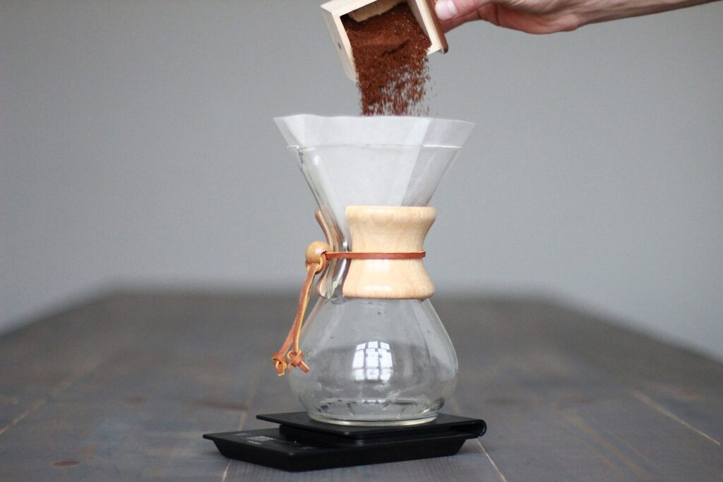 Kaffeepulver wird in eine Chemex-Karaffe mit Papierfilter gefüllt, die auf einer Waage steht