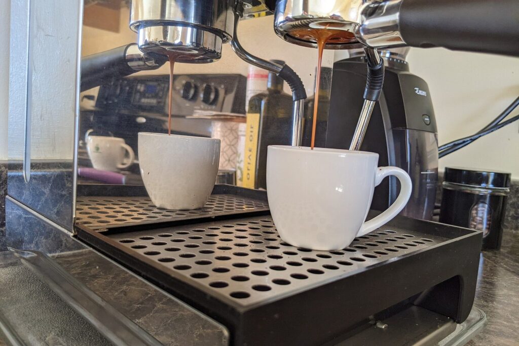 Espresso läuft aus dem Siebträger einer Espressomaschine in zwei Tassen