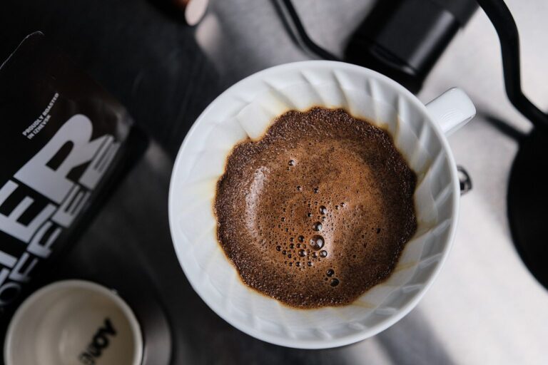 Heißes Wasser wird aus einem Kessel über einen Handfilter mit Kaffeepulver gegossen