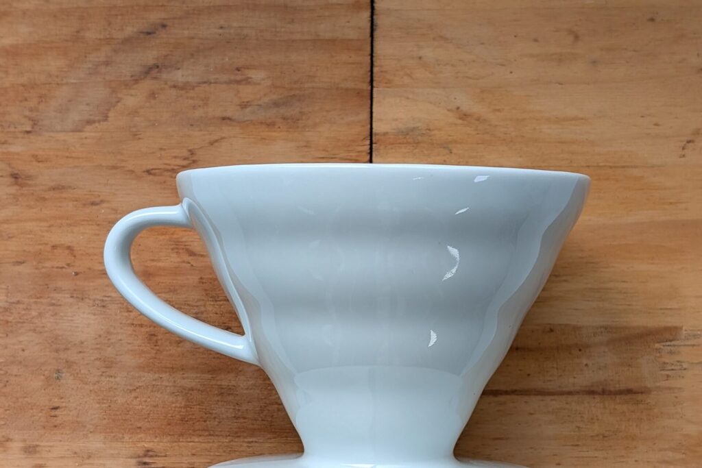 Weißer Keramik-Handfilter V60 auf einem Holztisch