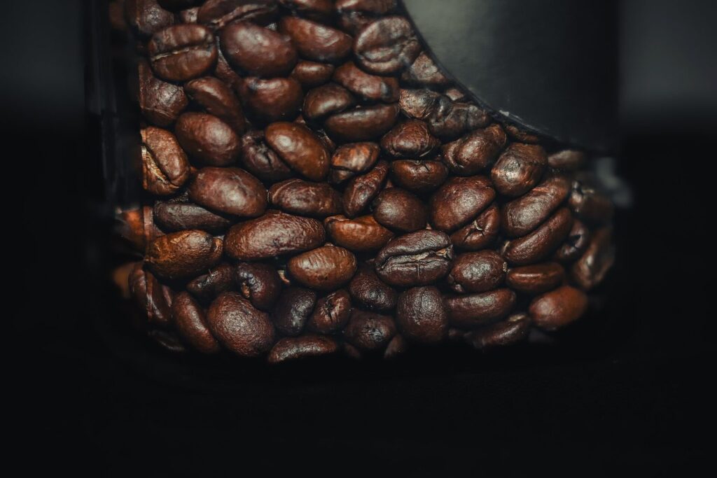Geröstete Kaffeebohnen in einem Glas vor dunklem Hintergrund