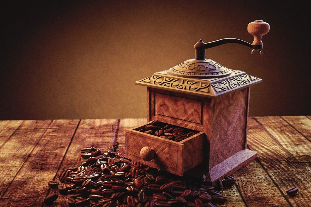 Alte Kaffeemühle aus Holz mit Schublade und Kaffeebohnen auf einem Holztisch