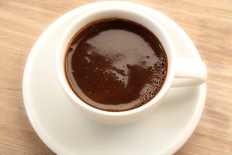 Weiße Tasse mit schwarzem Kaffee auf einer Untertasse